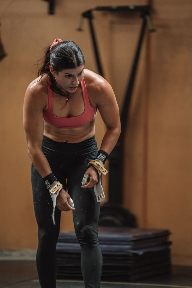 Athlete in grips catching her breath between workouts