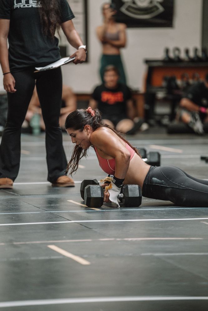 Athlete on a dumbbell push-up while her judge counts reps